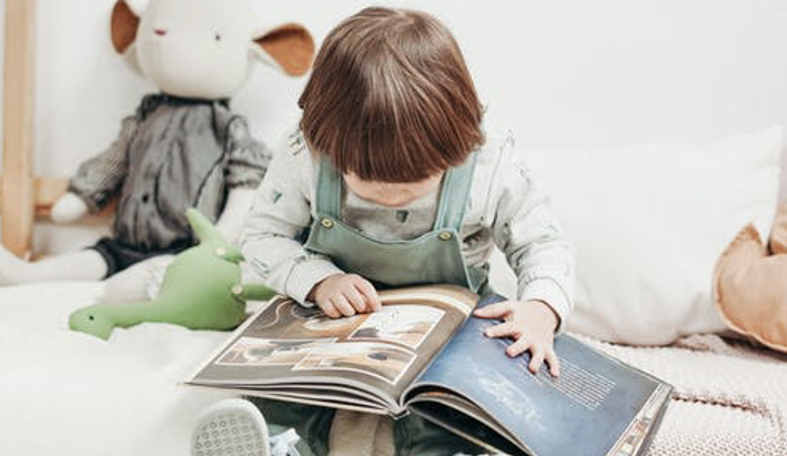 Young child reading a book on his bed